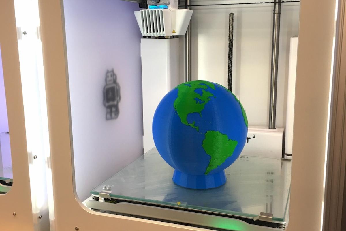 Ultimaker 3D printer printing an Earth globe that is green (land) and blue (water).