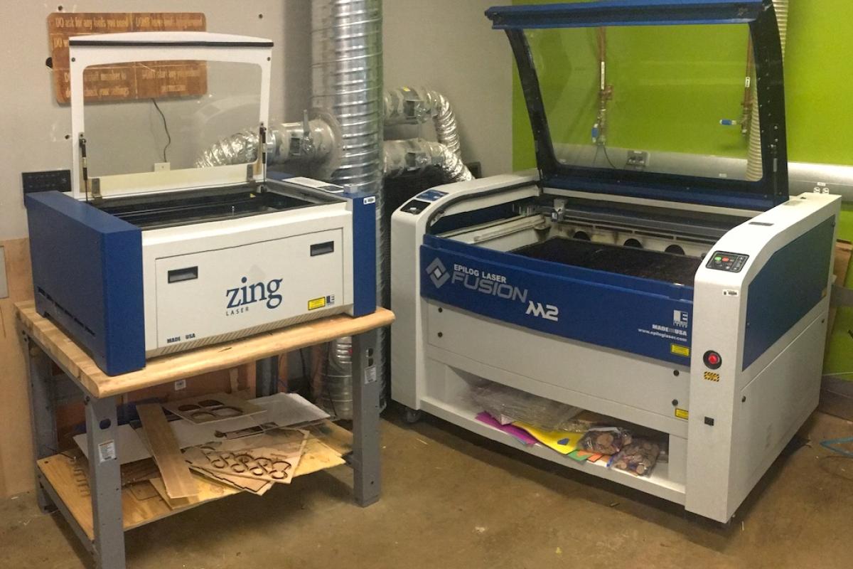 Epilog Zing and Fusion M2 laser cutters shown side by side.